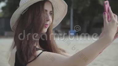 夏天<strong>戴</strong>着白色帽子的年轻女人在海滩上休息的<strong>手机</strong>上<strong>自拍</strong>的肖像。 夏日休闲